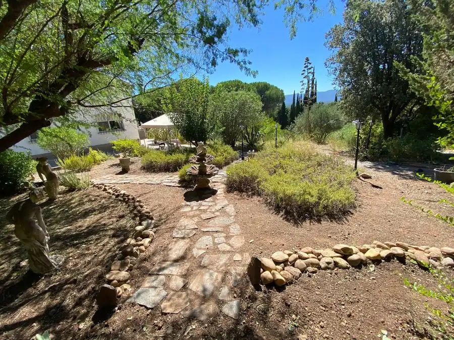 Jardin sec avec chemin en pierre, massifs paillés et bordure de galets devant une villa à Roquebrune-sur-Argens